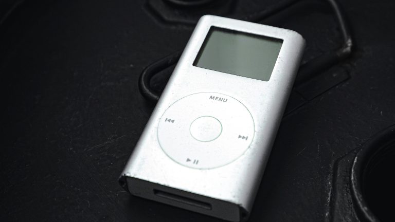 Ein silberner iPod der ersten Generation liegt auf einem schwarzen Untergrund.