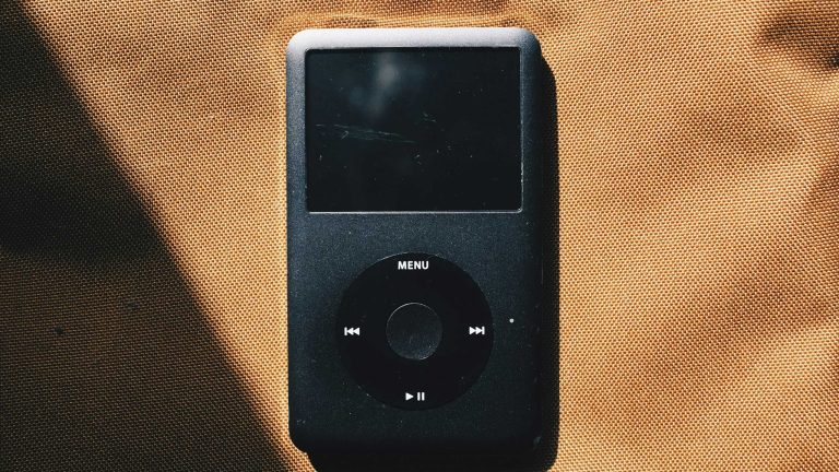 Ein schwarzer iPod liegt auf einem cognacfarbenen Untergrund.