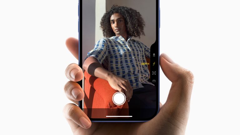 Eine Person hält ein iPhone 16 Pro Max in der Hand, um ein Foto einer Person zu machen. Dabei wechselt sie die Brennweite durch Drücken des Action Buttons.