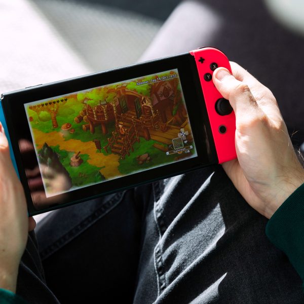 Eine Person hält eine Nintendo Switch in der Hand und spielt darauf ein Cozy Game.